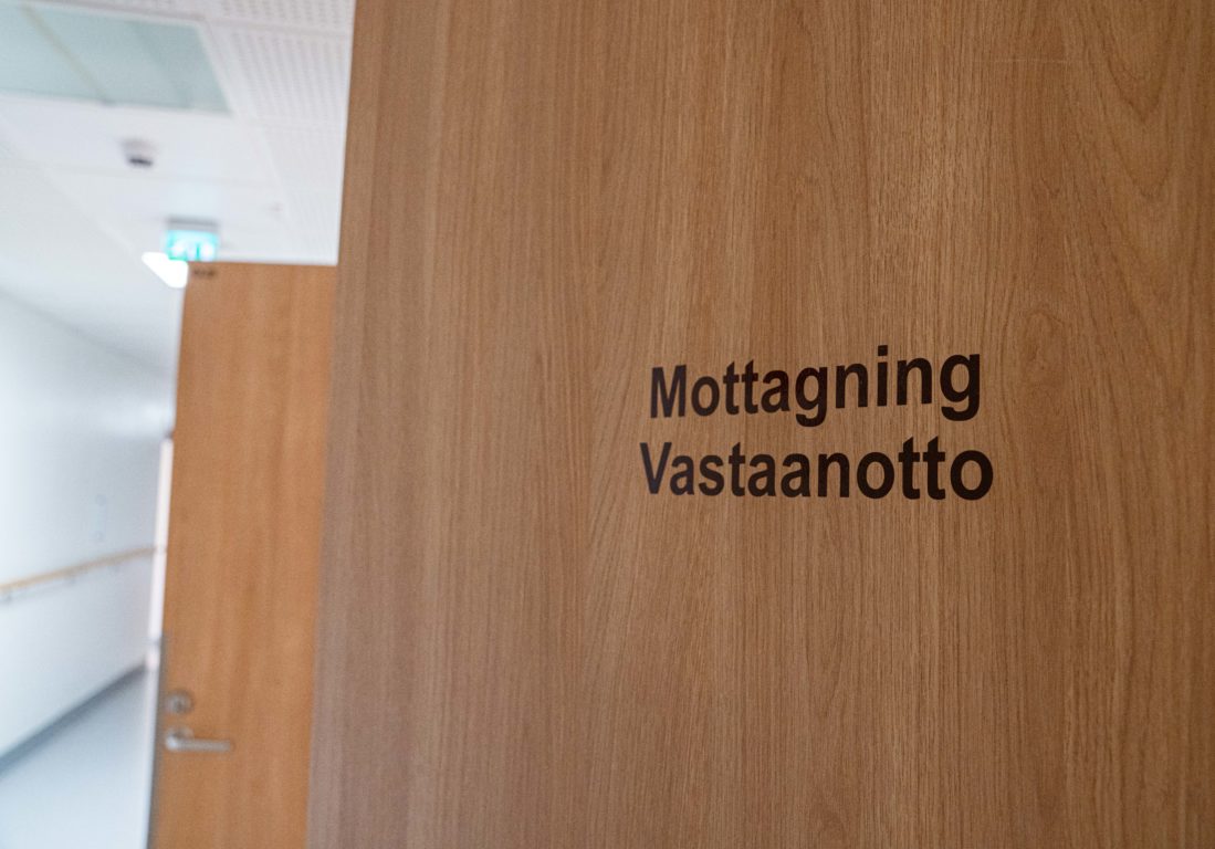 En öppen dörr där det står mottagning vastaanotto