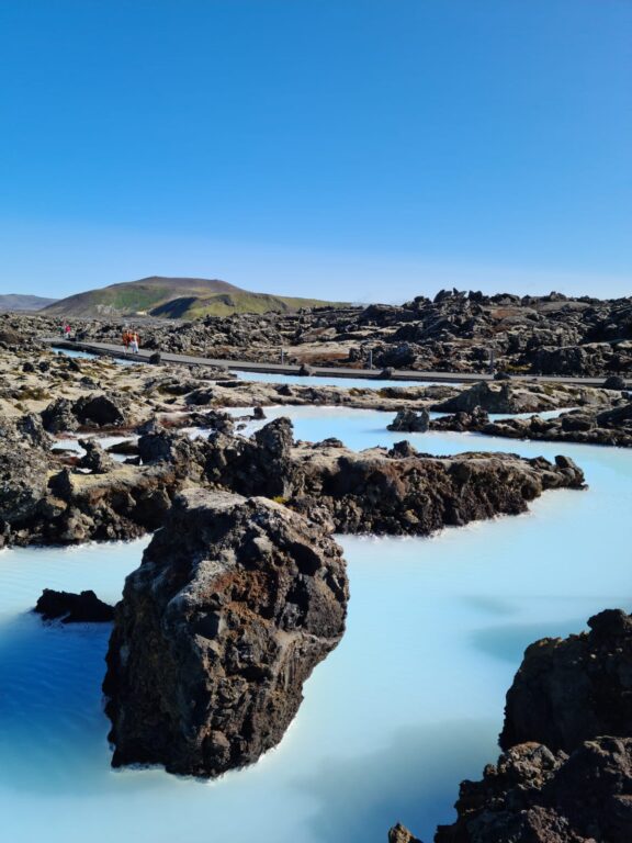 Blue Lagoon på Island, mörka stenformationer i ljusblått vatten.