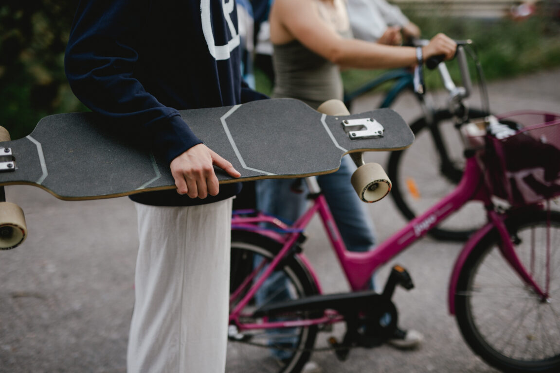 Ungdomar med skateboard och cykel.