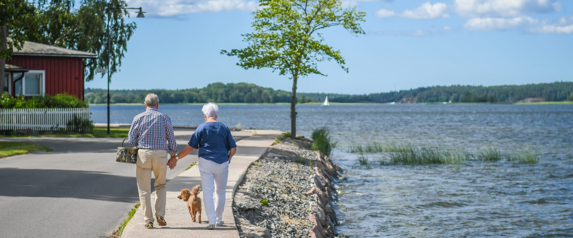 Ett äldre par går på Västvallen med sin hund en vacker sommardag